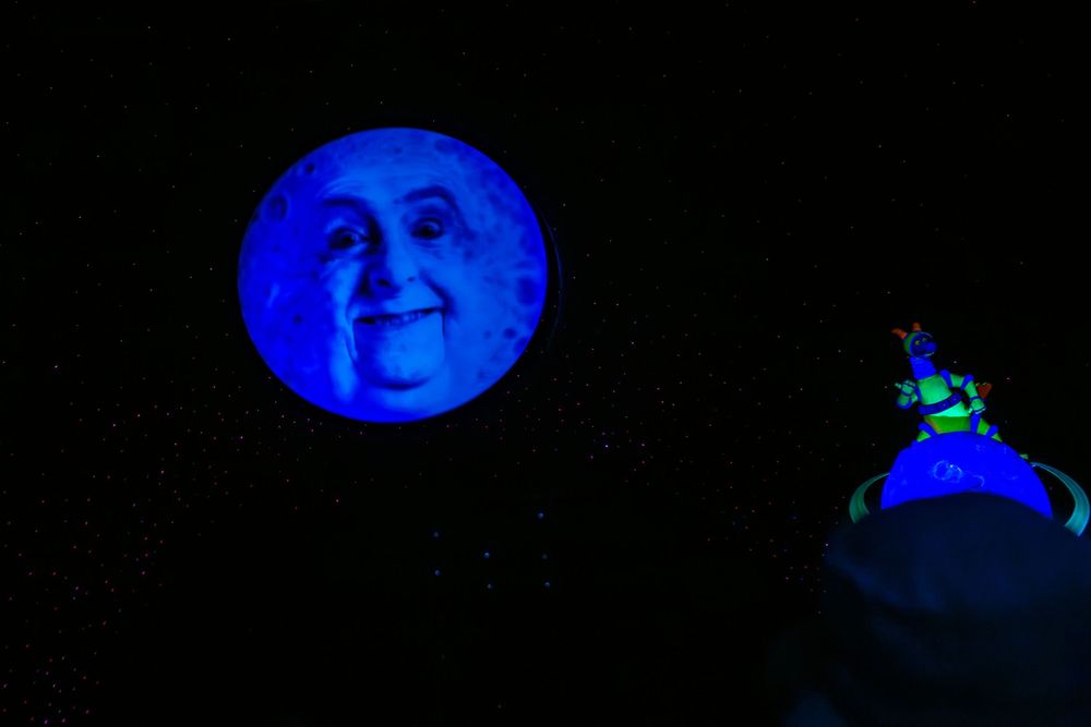 A series of blue-lit theatrical photos showing performers in silhouette against a dark background.