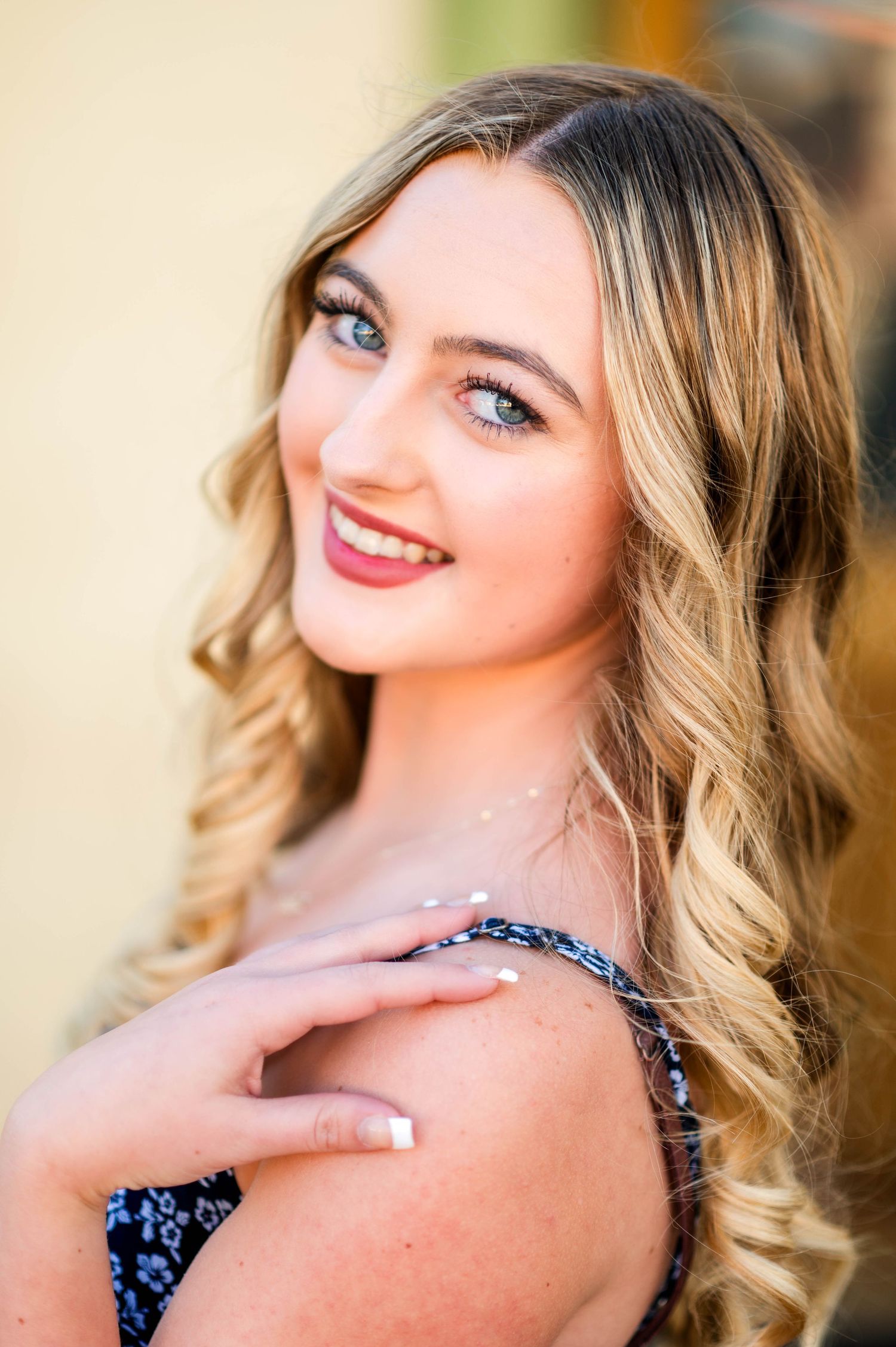 Close-up portrait of a blue-eyed blonde young woman smiling with glitter on her skin outdoors.