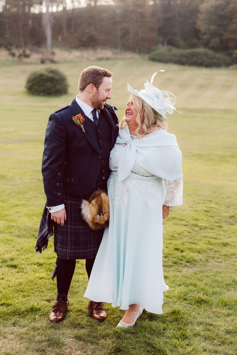 A couple shares a romantic moment outdoors in a grassy field on their wedding day.