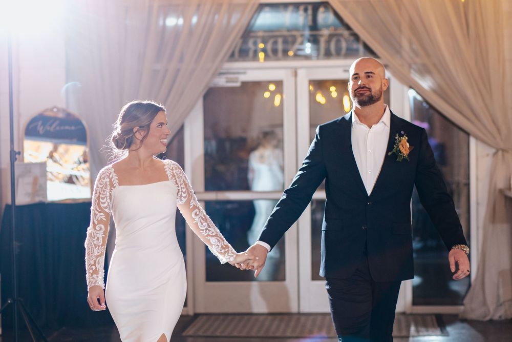 Couple shares their first dance at a wedding reception in an elegantly decorated venue with white drapes.