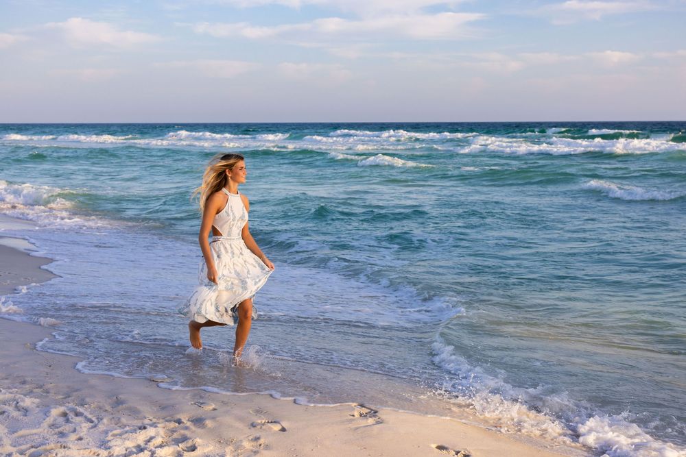 A series of connected beach photos showing waves crashing on shore and someone walking along the sandy coastline.