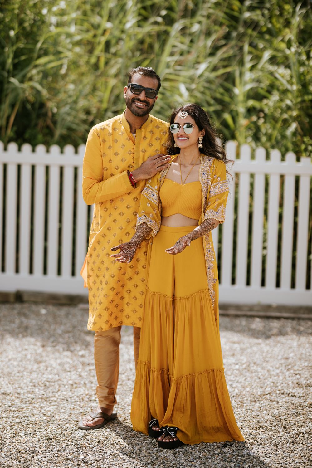 A couple shares a joyful moment wearing matching mustard yellow traditional Indian attire outdoors.