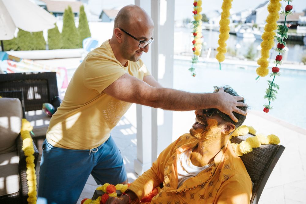 A person in a yellow shirt carves intricate designs into a large orange pumpkin during a pumpkin carving demonstration.