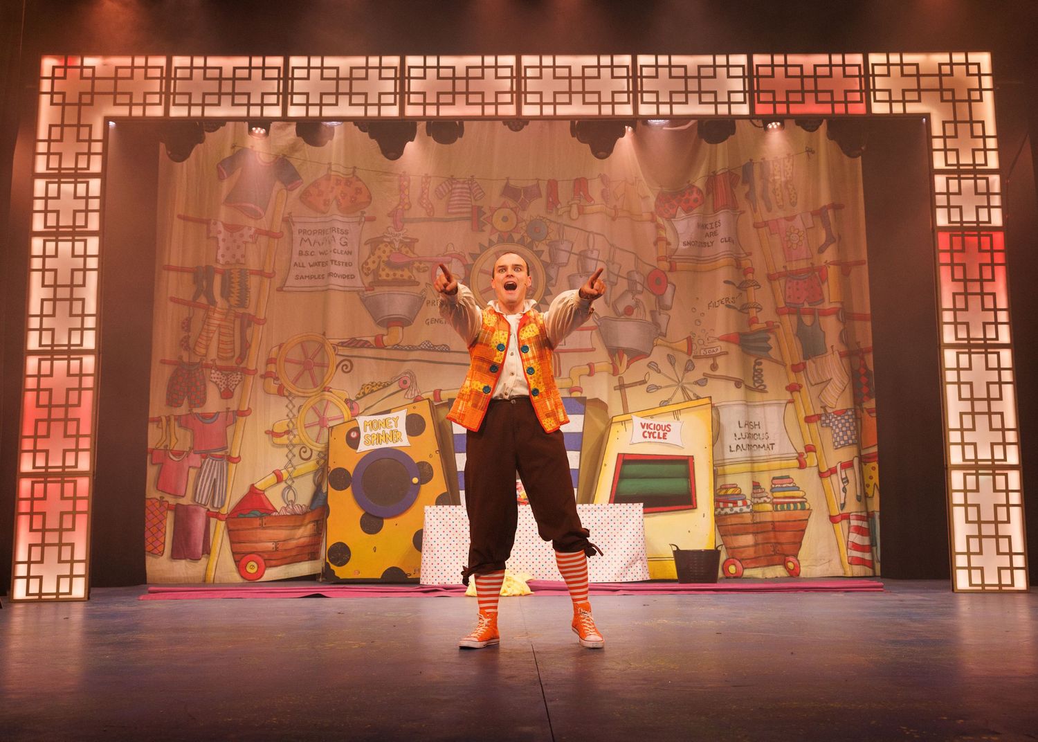 Theater performers dancing on stage with ornate gold-framed backdrop and dramatic lighting during a musical production.