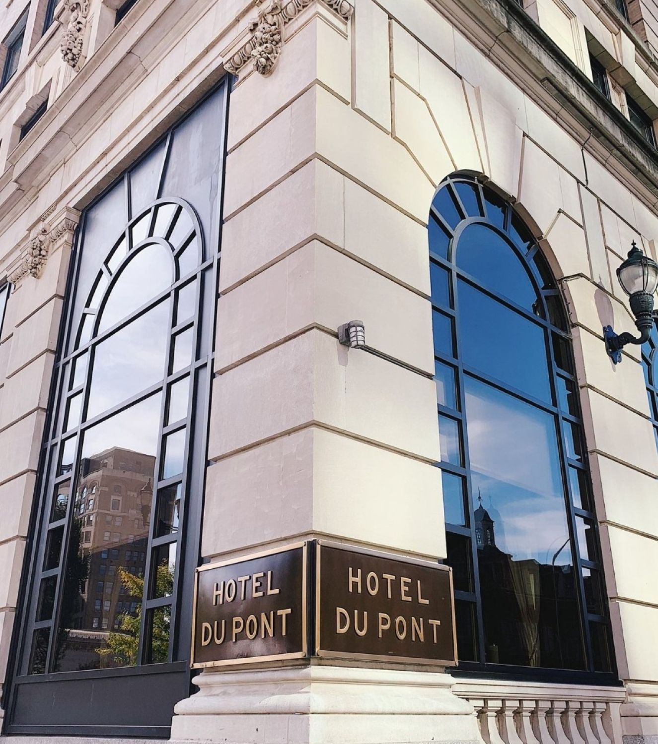 Exterior view of Hotel Du Pont with multiple arched windows and gold lettering signage on a white stone facade.