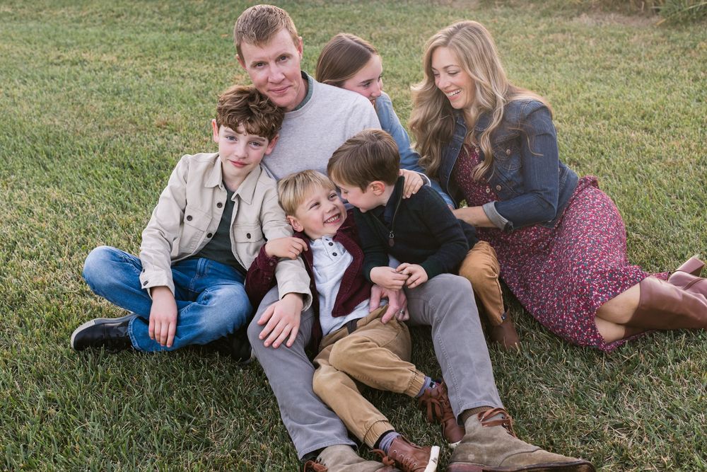 A family lounges on one another on grass for family photos in the Seacoast, Rye, Hampton, New Hampshire, Southern Maine family photographer.