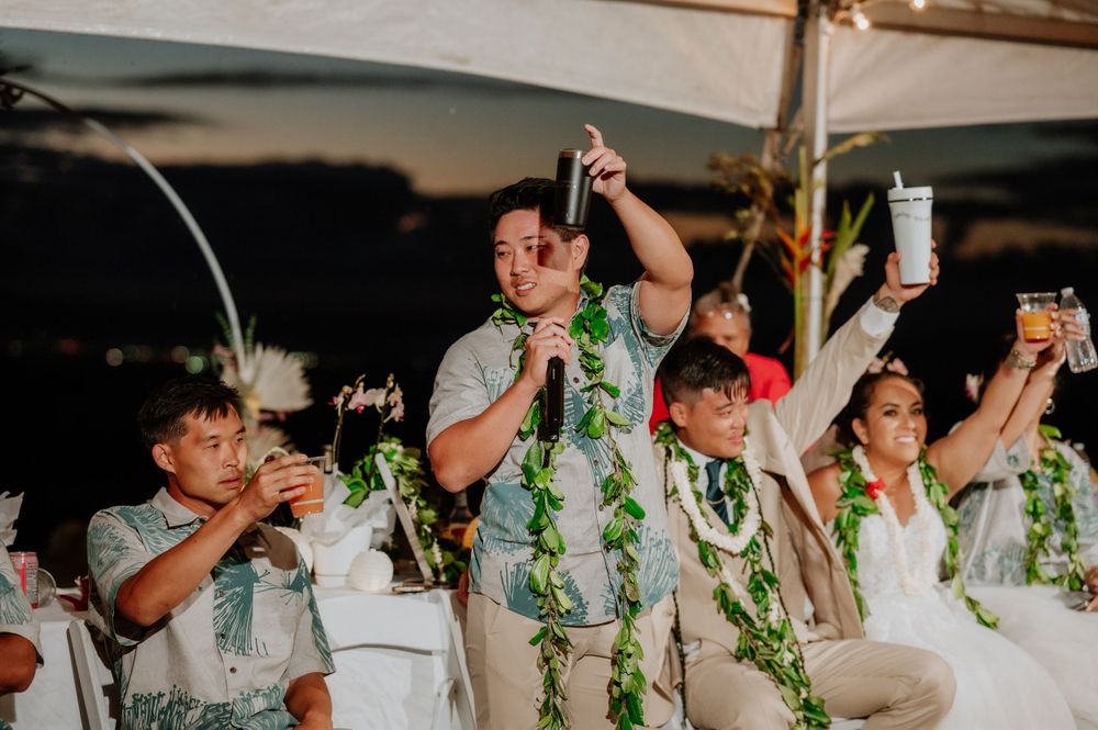 Wedding party members wearing white and green leis dance together at the reception.