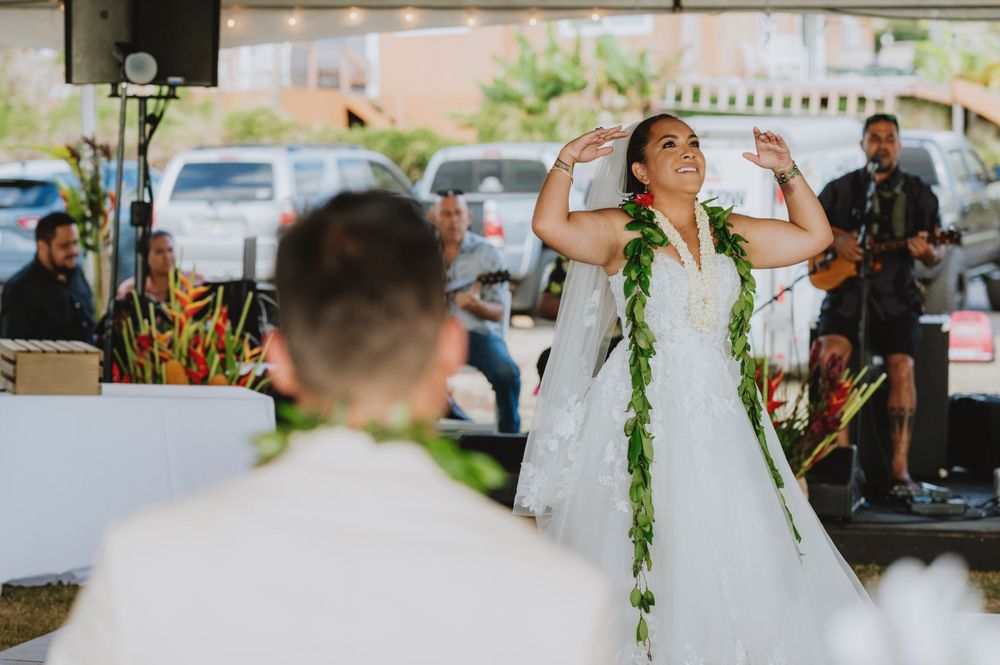 Bride dancing joyfully at outdoor reception with live band performing in background.