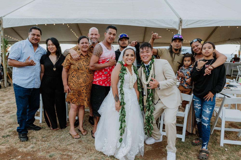 Wedding party and guests pose together for a group photo under the reception tent.