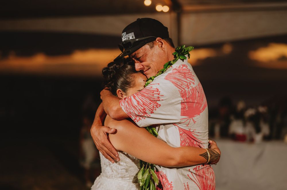 A couple embraces on the dance floor under warm lighting at a wedding reception.
