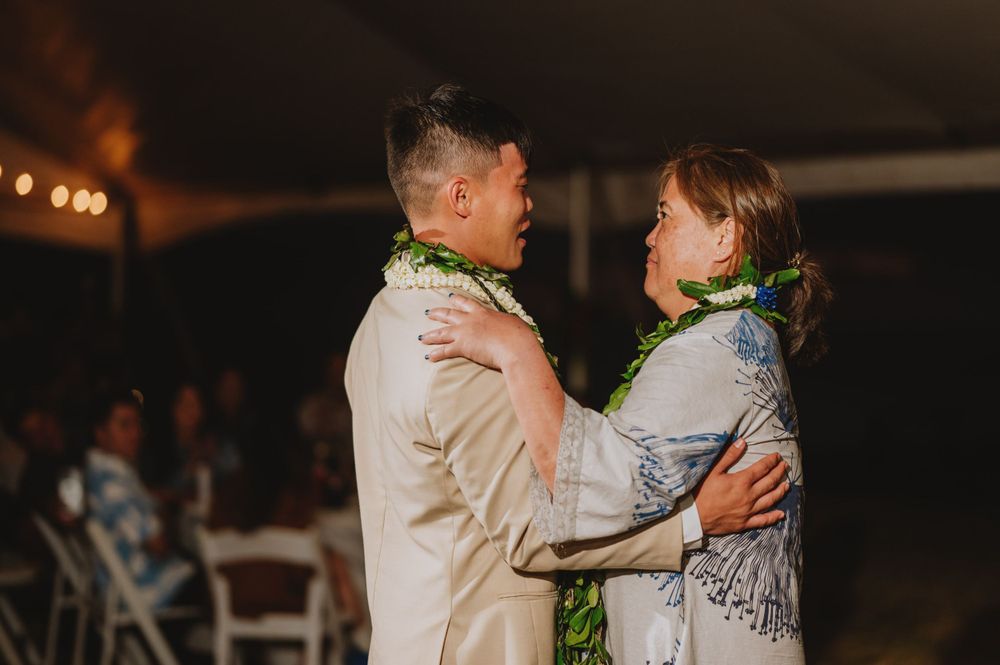 Wedding guests dance together under string lights at an evening reception celebration.