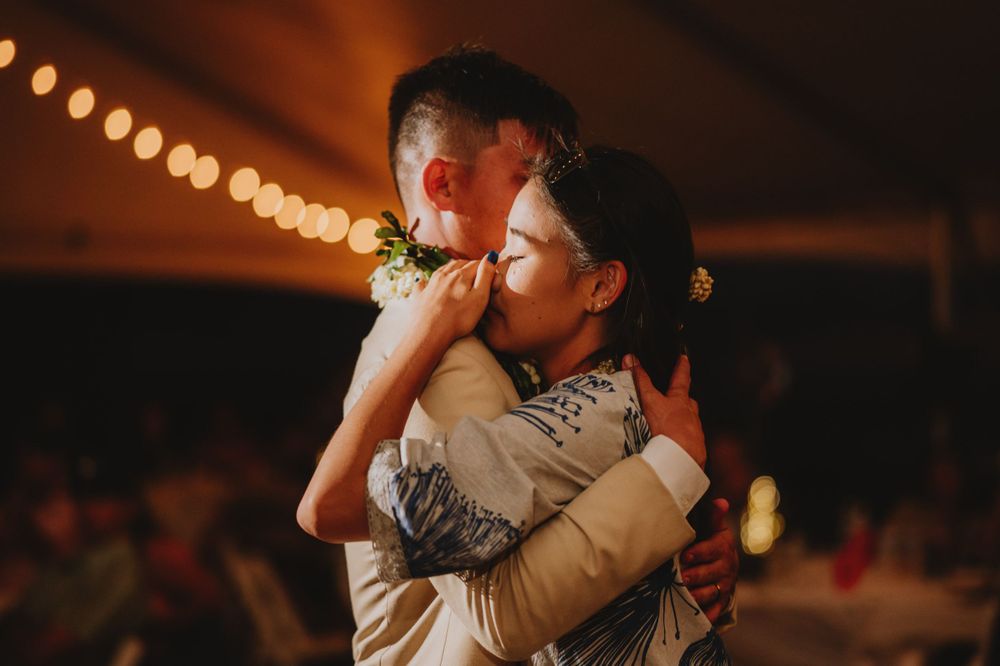 Dancers perform in a line under string lights at an outdoor wedding reception.
