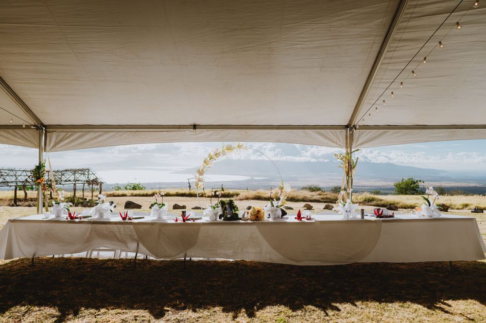 Wedding reception tables set up under a white tent with ocean views in the background.