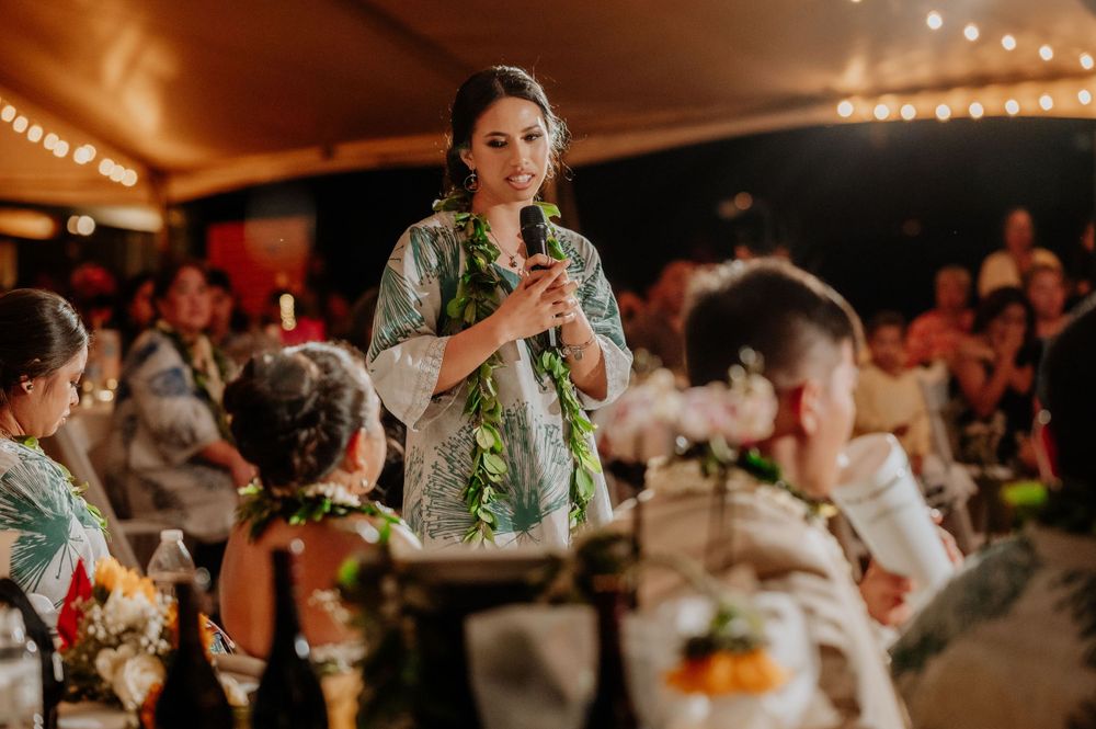Wedding reception guests dance and celebrate under warm string lighting.