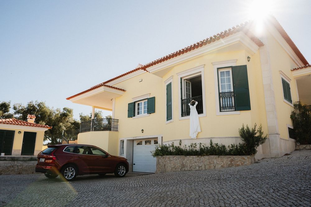 Mediterranean style villa with white walls and terracotta roof tiles in a residential complex with paved driveway.