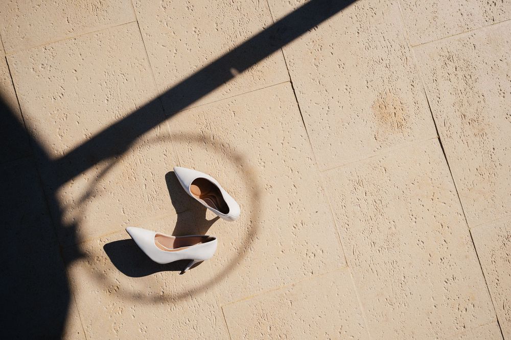 Overhead view of a person sitting with laptop in circular spotlight created by shadow and sunlight on beige floor.