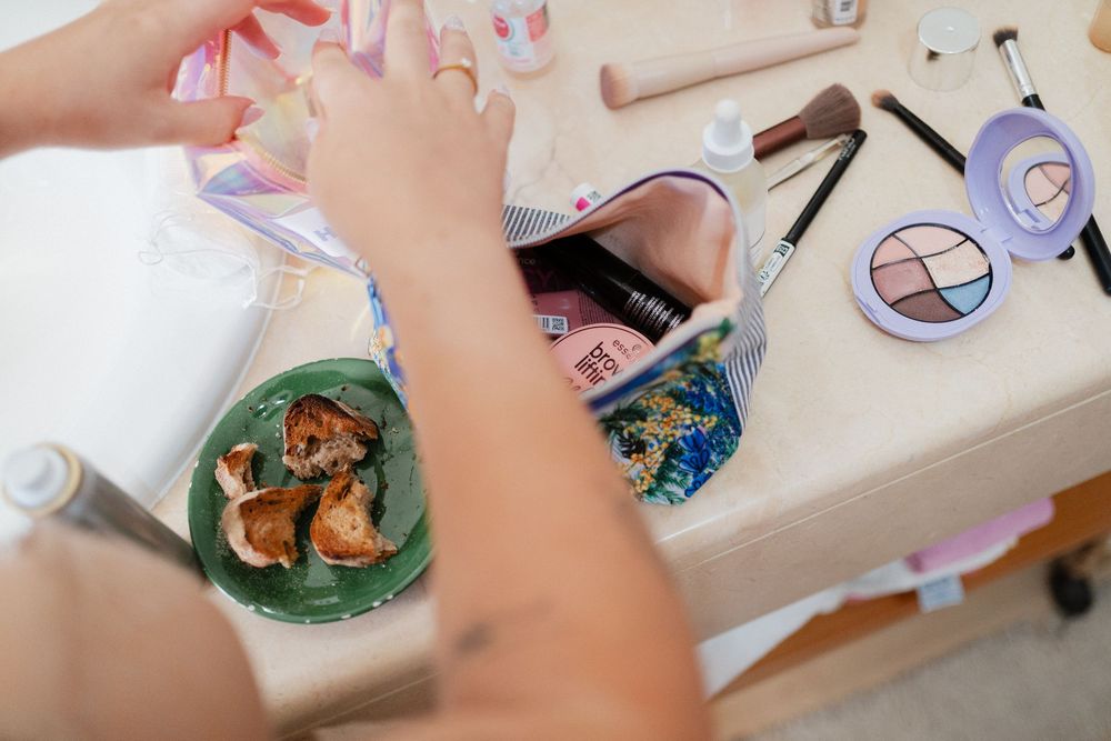Close-up view of hands working on a craft project with colorful supplies and materials on a white table surface.