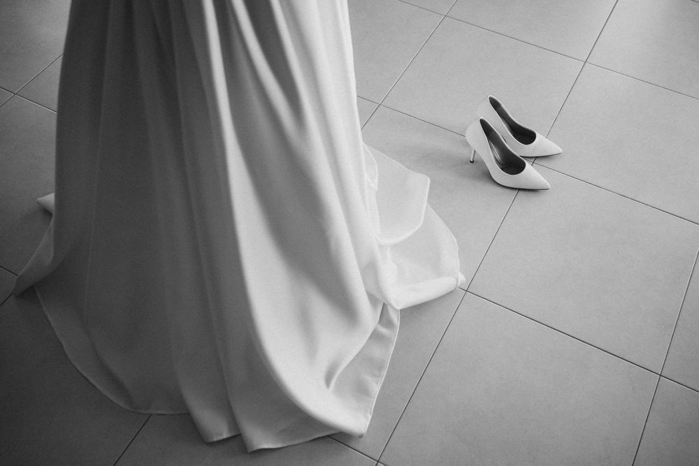 A bride in a flowing white wedding dress walks across a polished gray tile floor.