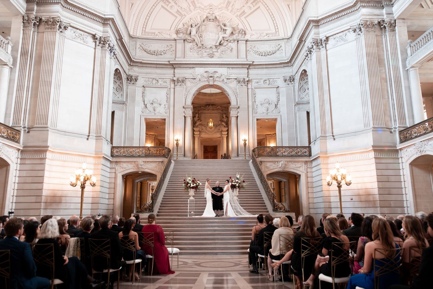 Elegant white and gold baroque concert hall with ornate ceiling details and chandeliers during a performance.