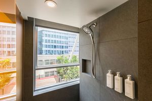 Contemporary bathroom interior with large windows showcases natural light and neutral color scheme.