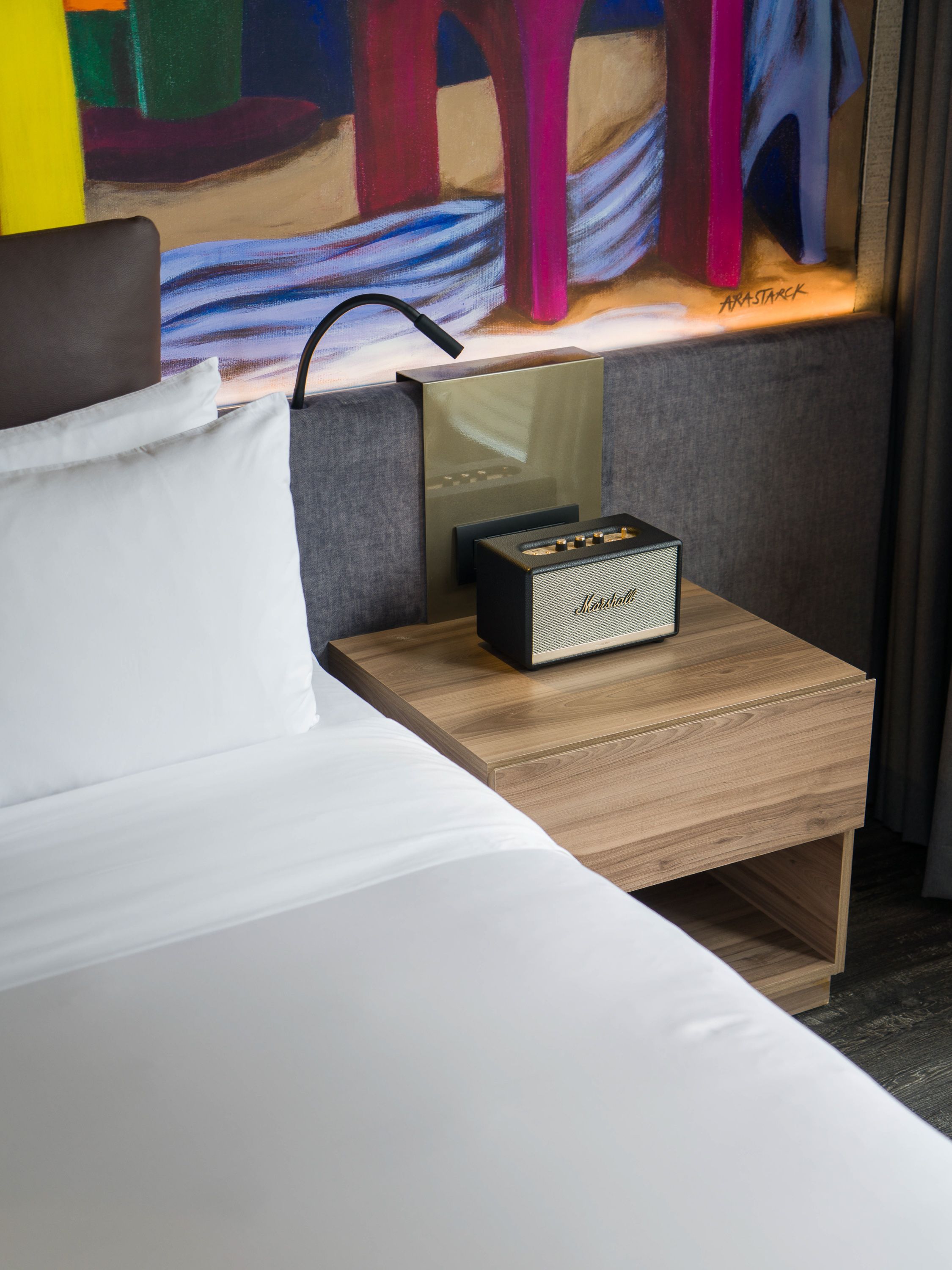 Modern hotel room interior with wooden furniture and colorful accent wall featuring contemporary design elements.