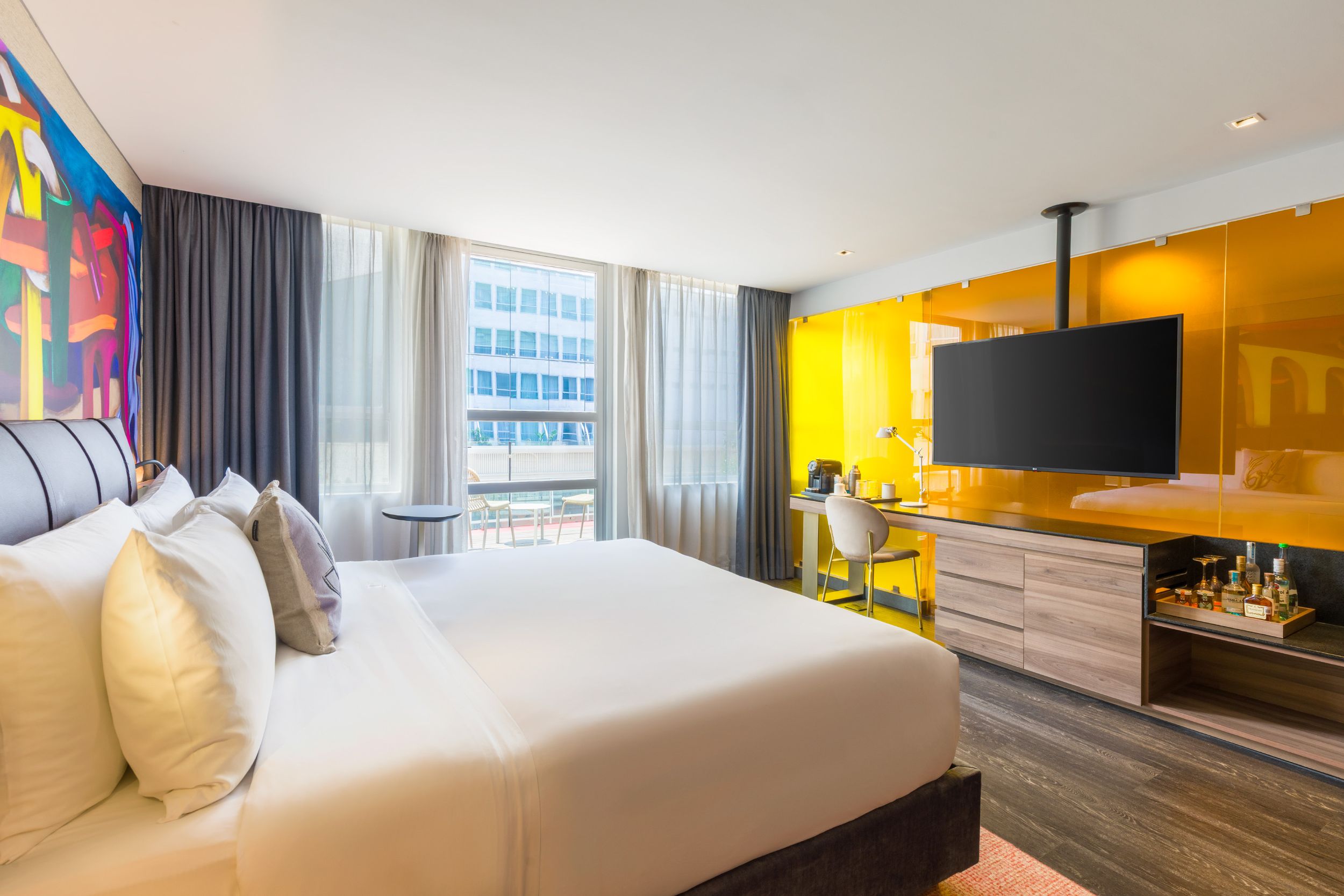 Modern hotel room interior with floor-to-ceiling windows, contemporary furnishings, and city views.