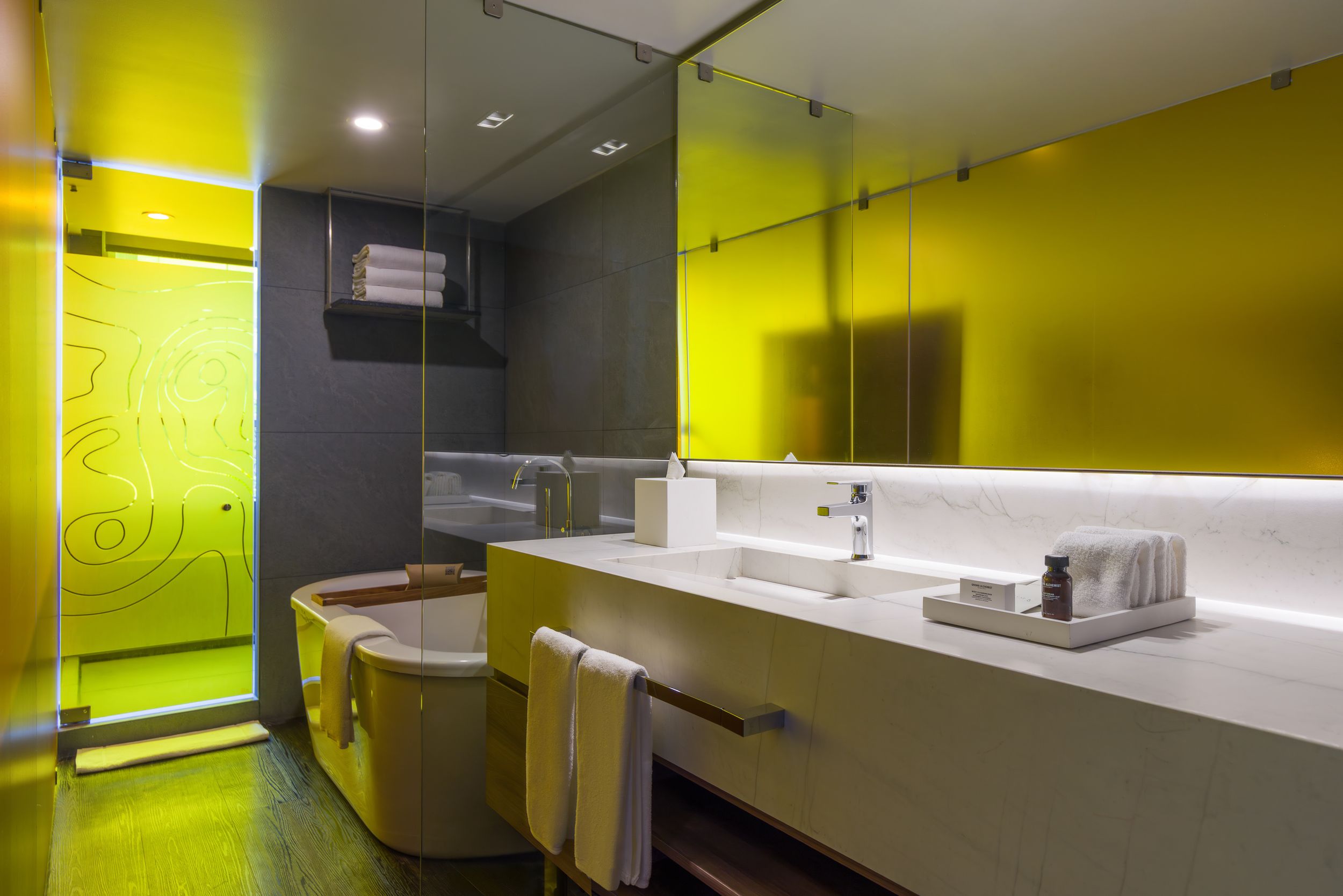 Contemporary bathroom design with bright yellow walls and modern fixtures under recessed lighting.