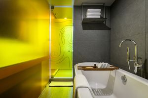 Minimalist bathroom with dramatic yellow lighting and concrete walls creating a moody atmosphere.