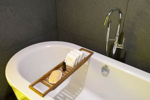 Modern bathroom interior with freestanding white bathtub, wooden accent shelf, and contemporary fixtures.