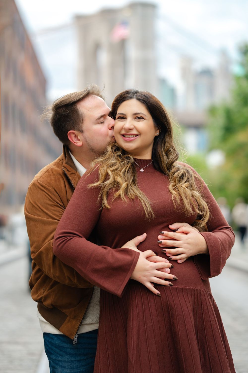 A romantic couple embracing outdoors wearing burgundy and brown clothing in an autumn setting.