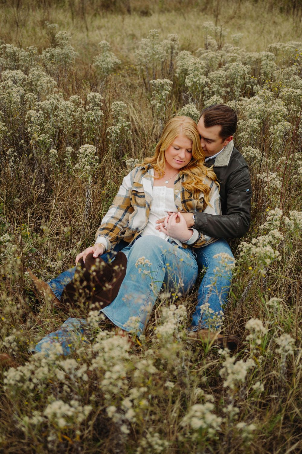 A couple shares intimate moments while laying in a wildflower meadow during a romantic outdoor photo session.