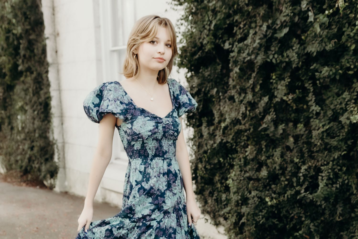 Outdoor portrait session featuring floral dress against stone wall backdrop.