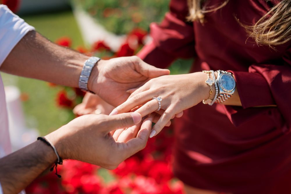 Hands releasing vibrant red rose petals outdoors in a celebratory gesture.