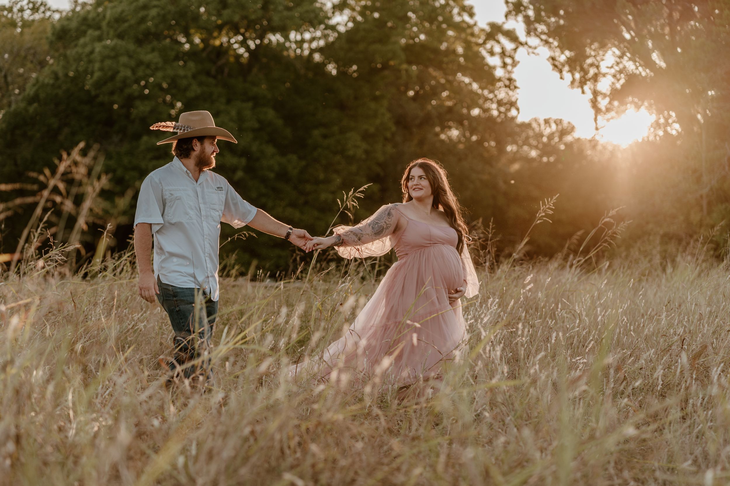 Romantic sunset photoshoot in a meadow with couple dancing through tall grass.