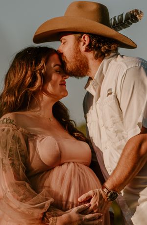 Romantic western-themed couple photoshoot with pink dress and cowboy hat.