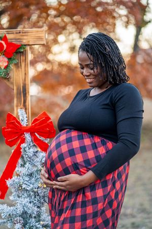 Festive maternity session with red bows and buffalo plaid dress.