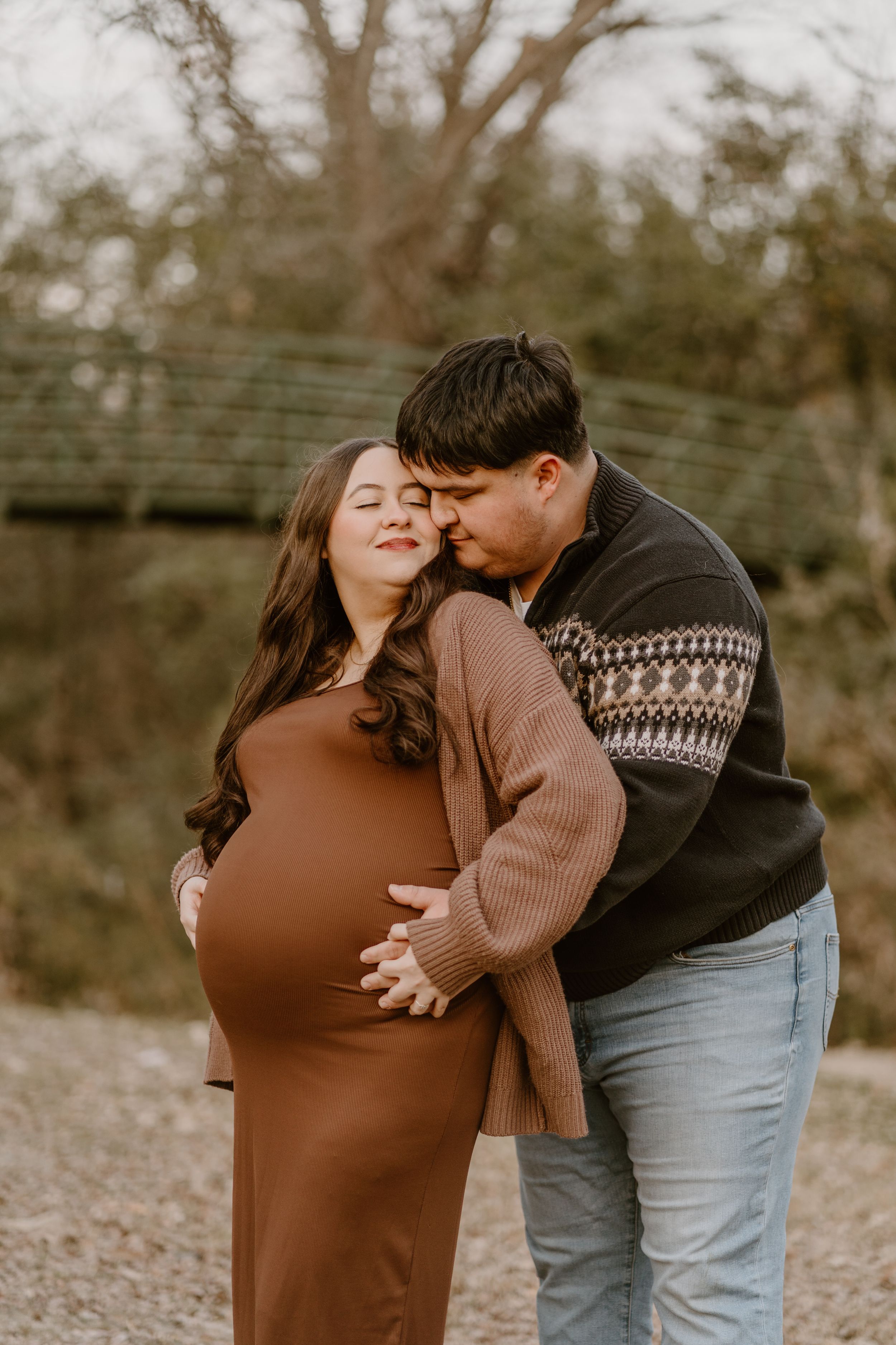 Romantic couple embracing outdoors wearing cozy sweaters.