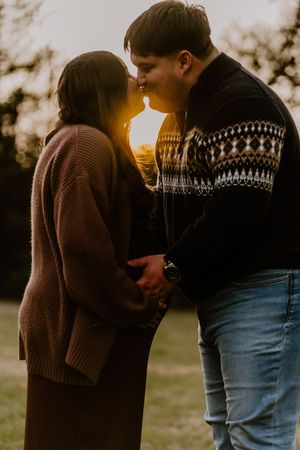 Sunset silhouette of couple sharing intimate moment outdoors.