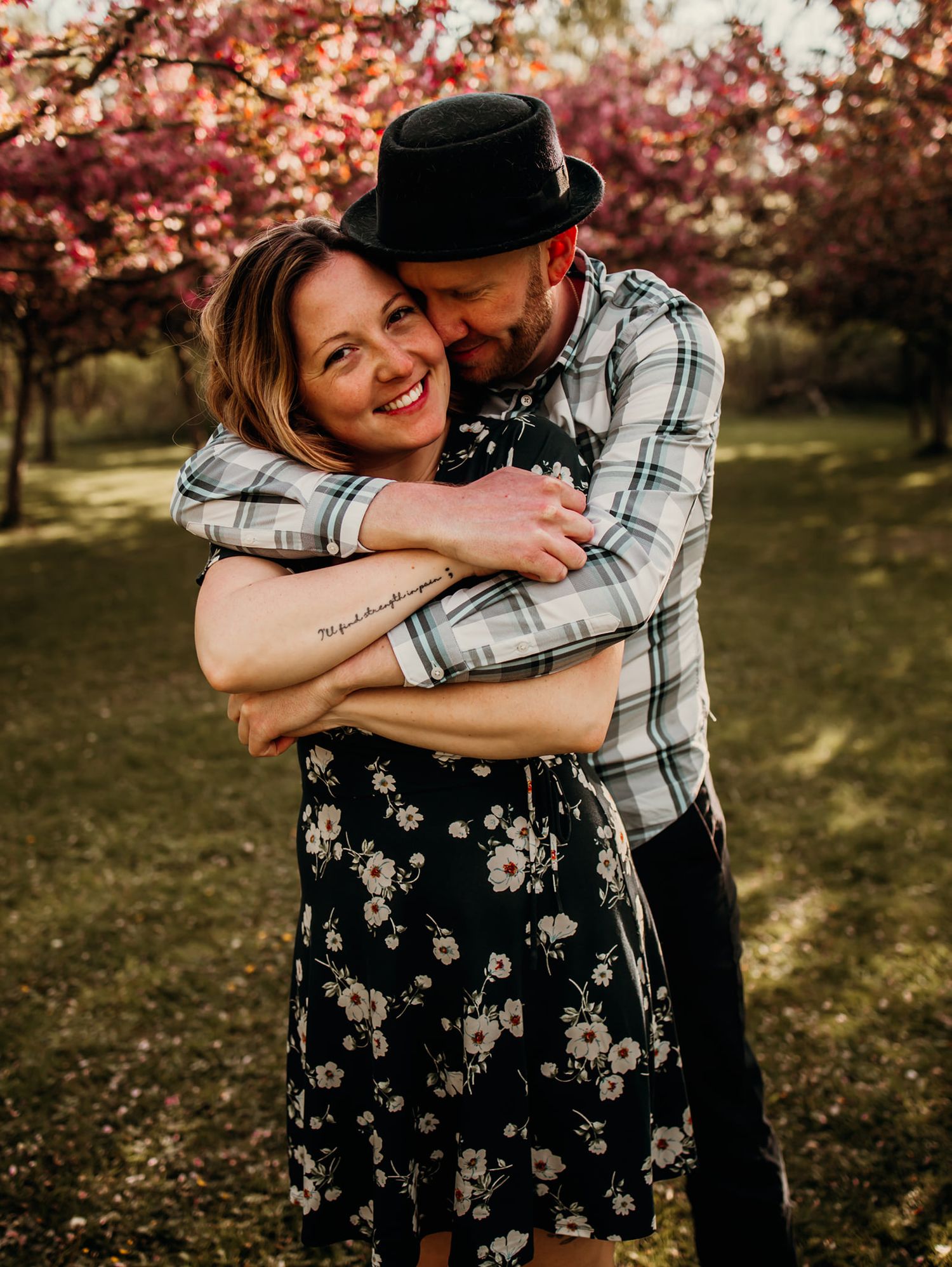 Playful couple hugging and laughing in a blooming spring garden.