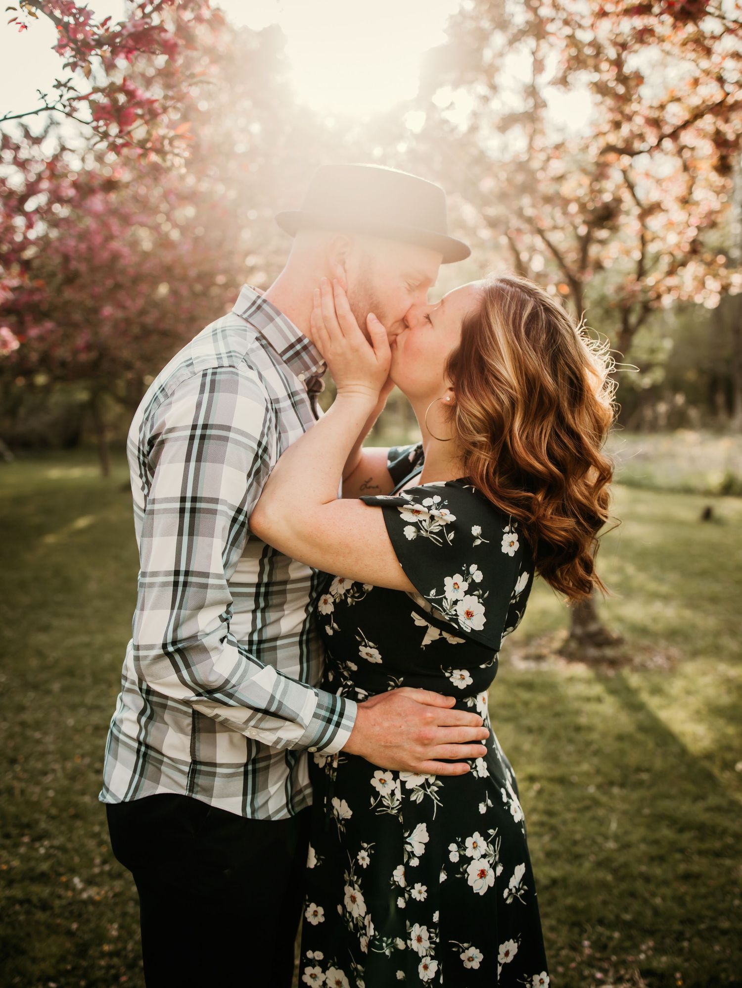 Romantic sunset engagement photo in spring orchard with blooming trees.