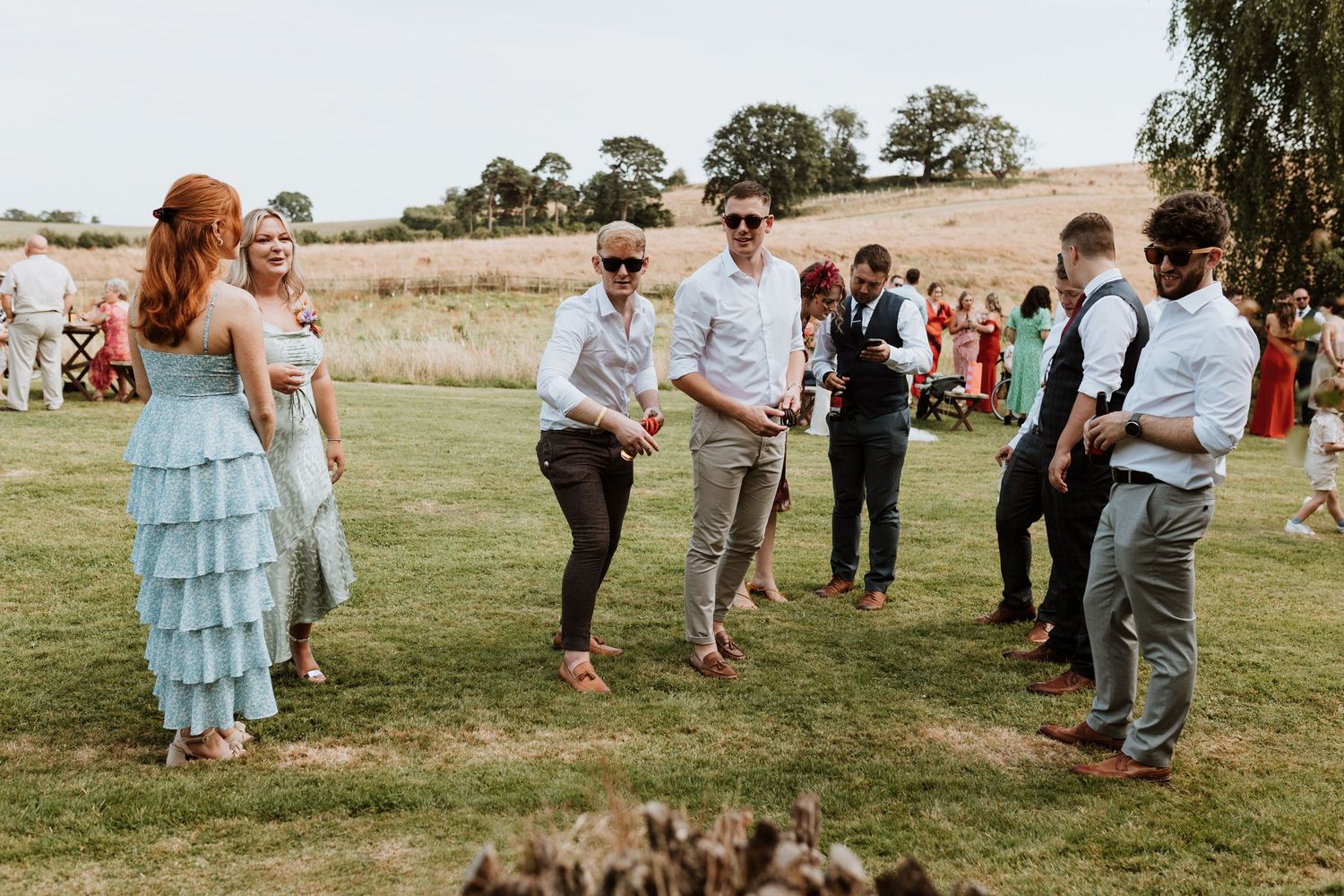 People playing games together outdoors on a grassy field during a casual outdoor celebration.
