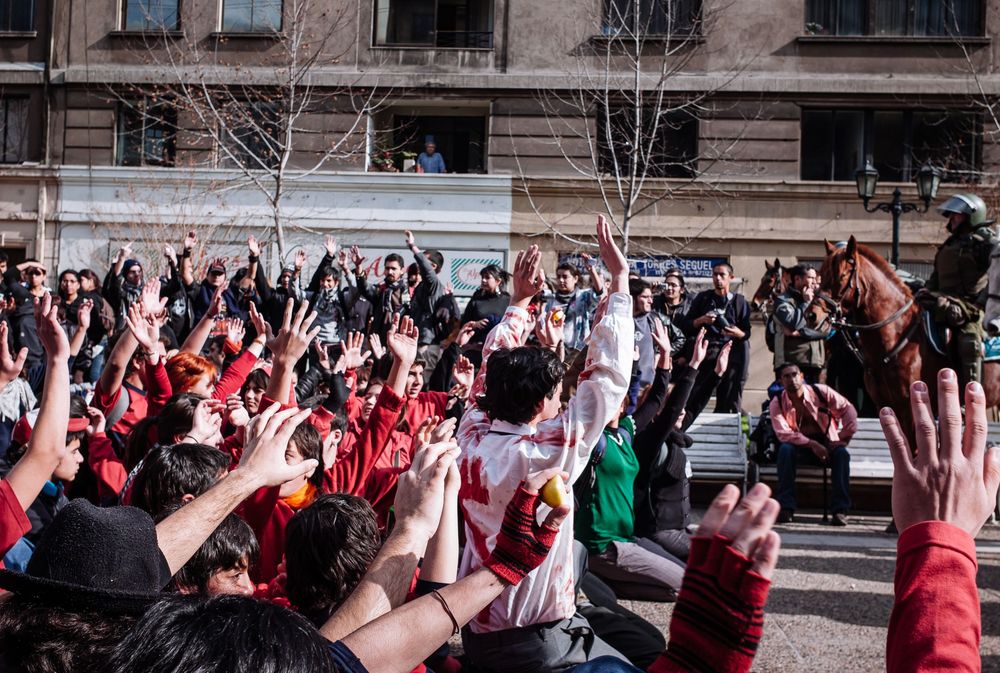 Large crowd with raised hands gathered outdoors during a street demonstration for a fairer education system. Santiago, Chile