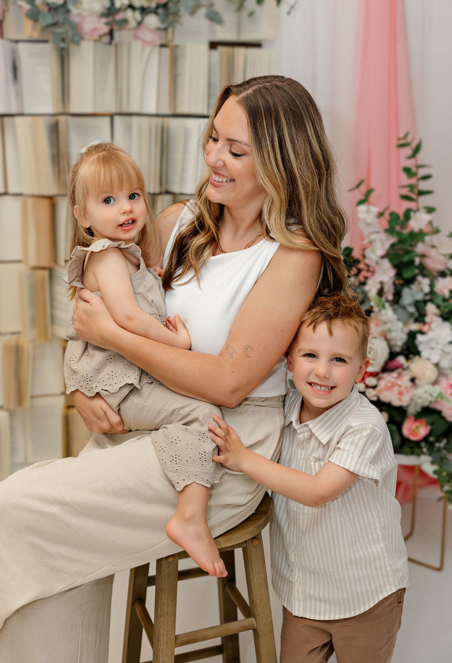 Family photoshoot in a bright studio with floral decorations and pink accents.