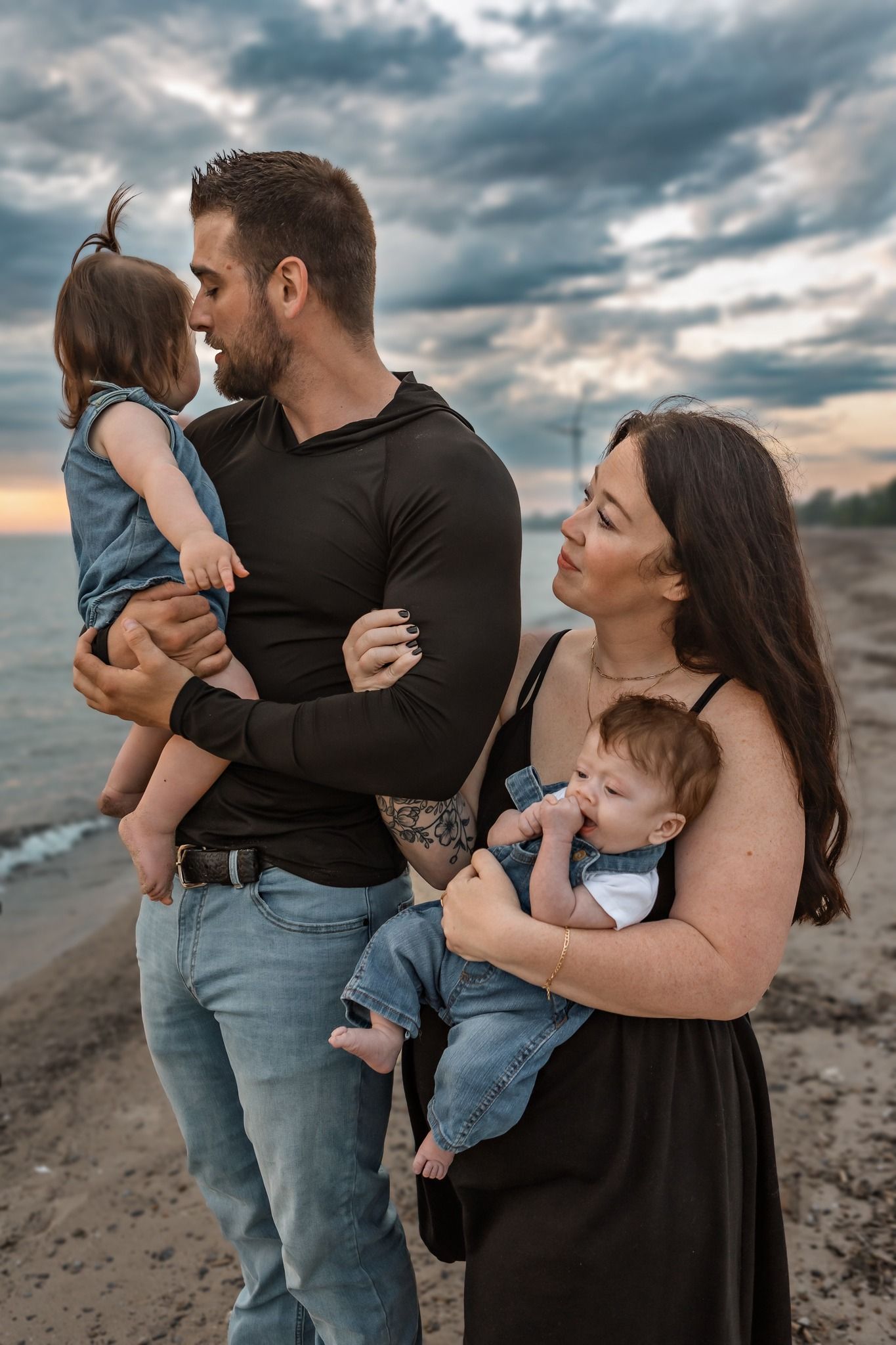Family portrait session on beach with moody cloudy sunset backdrop.