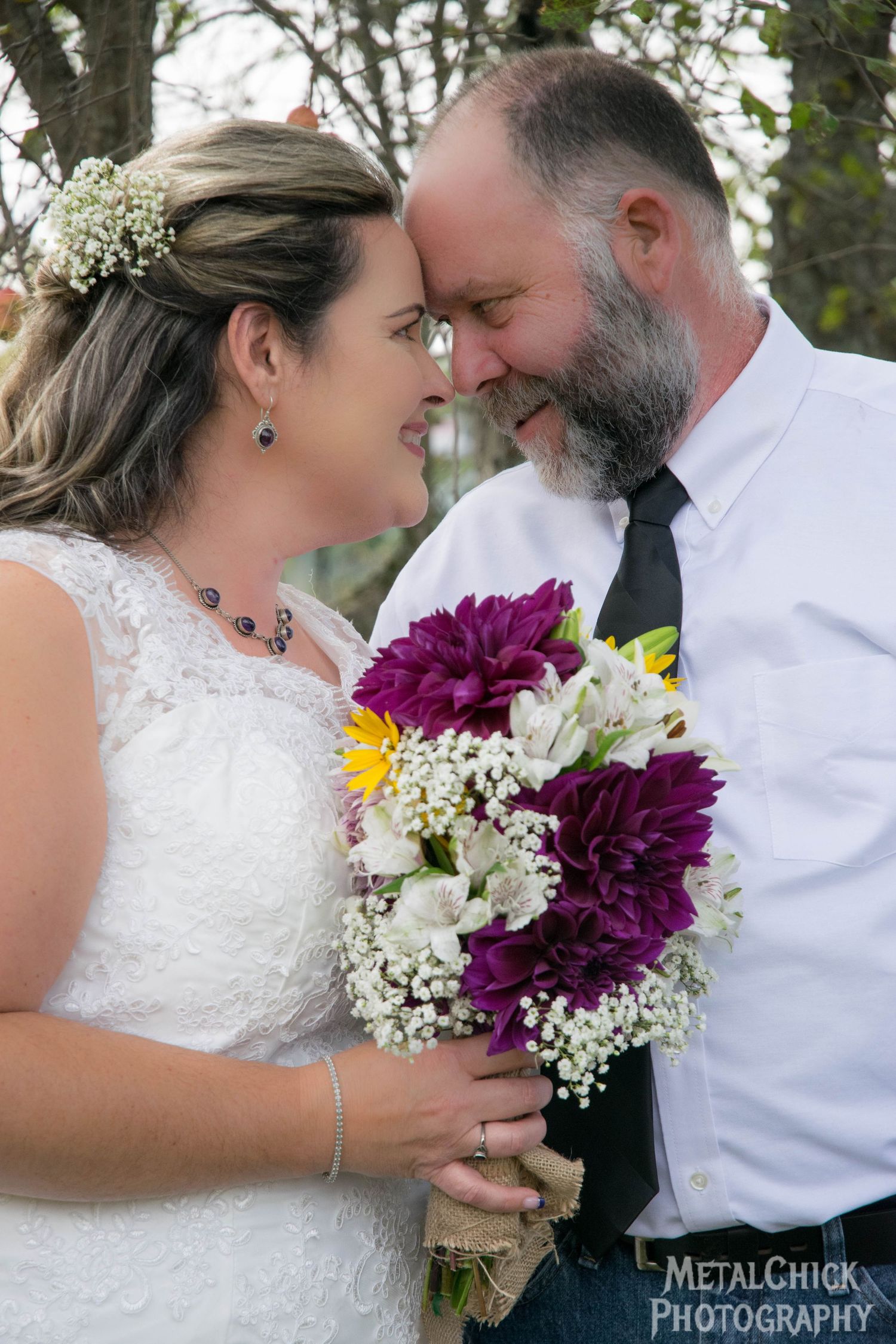 Wedding portrait by Northern Exposure featuring of a husband and wife looking at each other with flowers in the brides hand