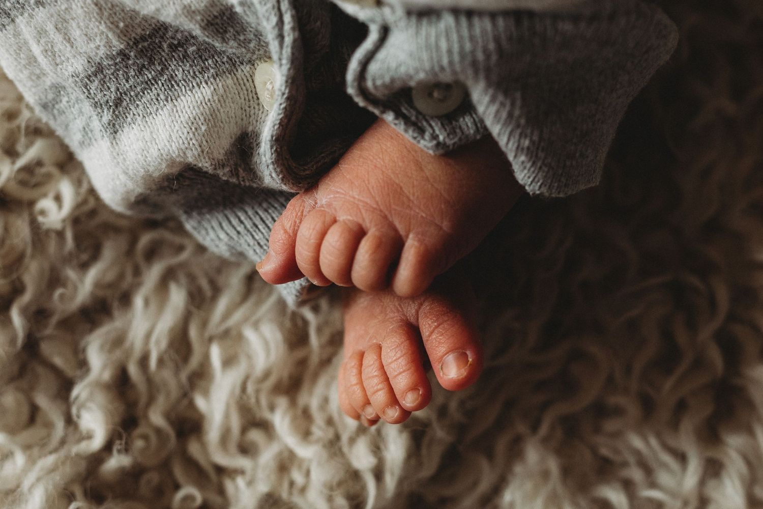Close up view of tiny baby feet resting on soft textured blanket in warm natural lighting.