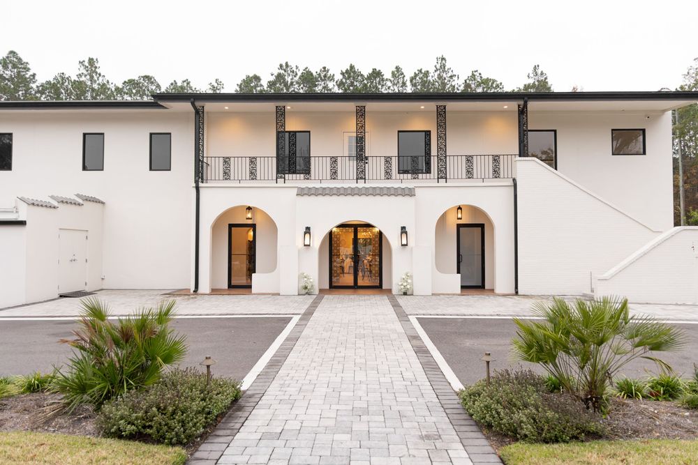 A modern Mediterranean-style white building with arched doorways and elegant stone walkways leading to the entrance.