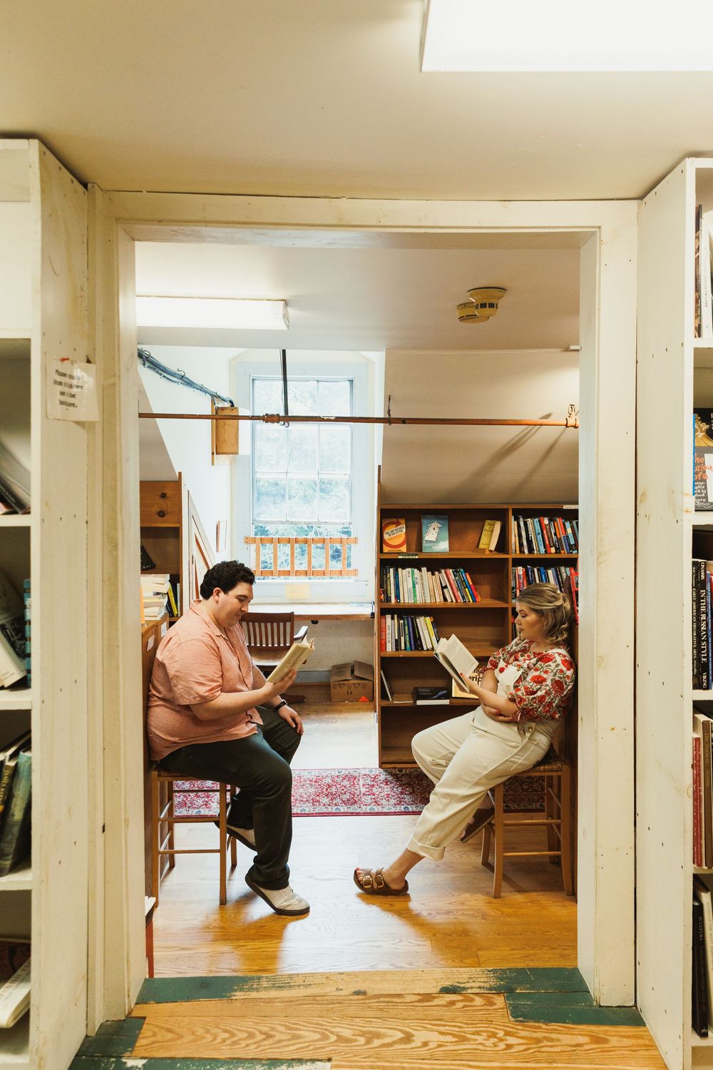 A bright library room with wooden floors and bookshelves along the walls.