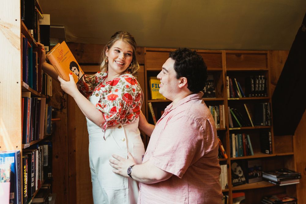 Two people engaged in playful interaction among library bookshelves.