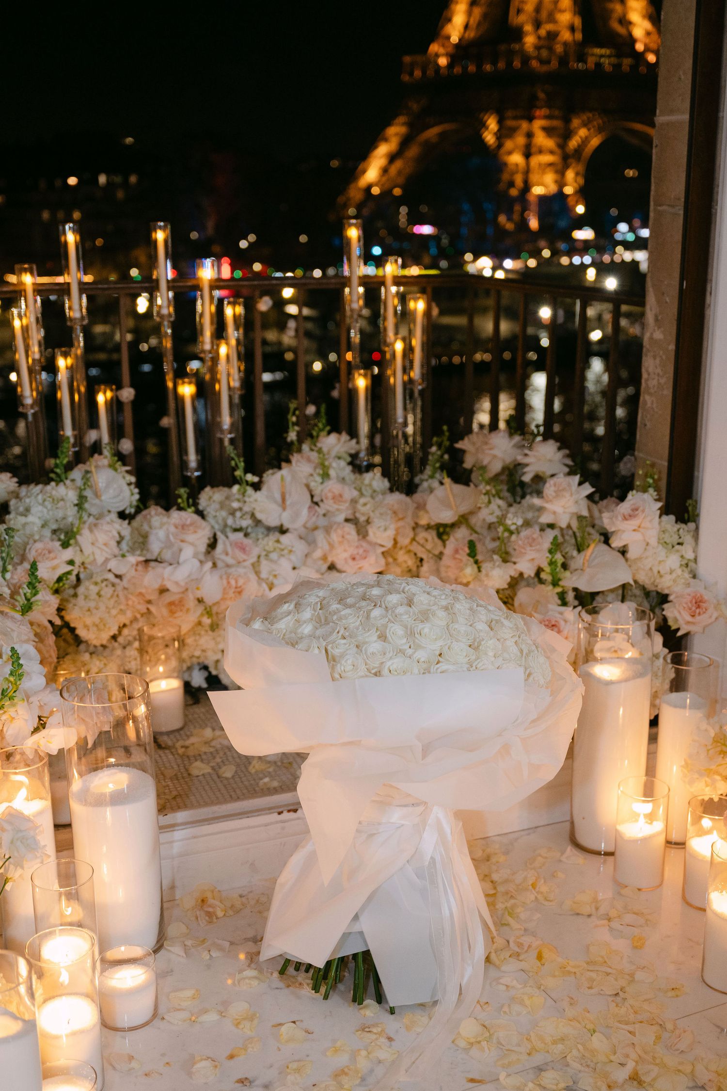 Elegant wedding reception table decorated with white flowers, candles and sheer fabric creating a romantic atmosphere.